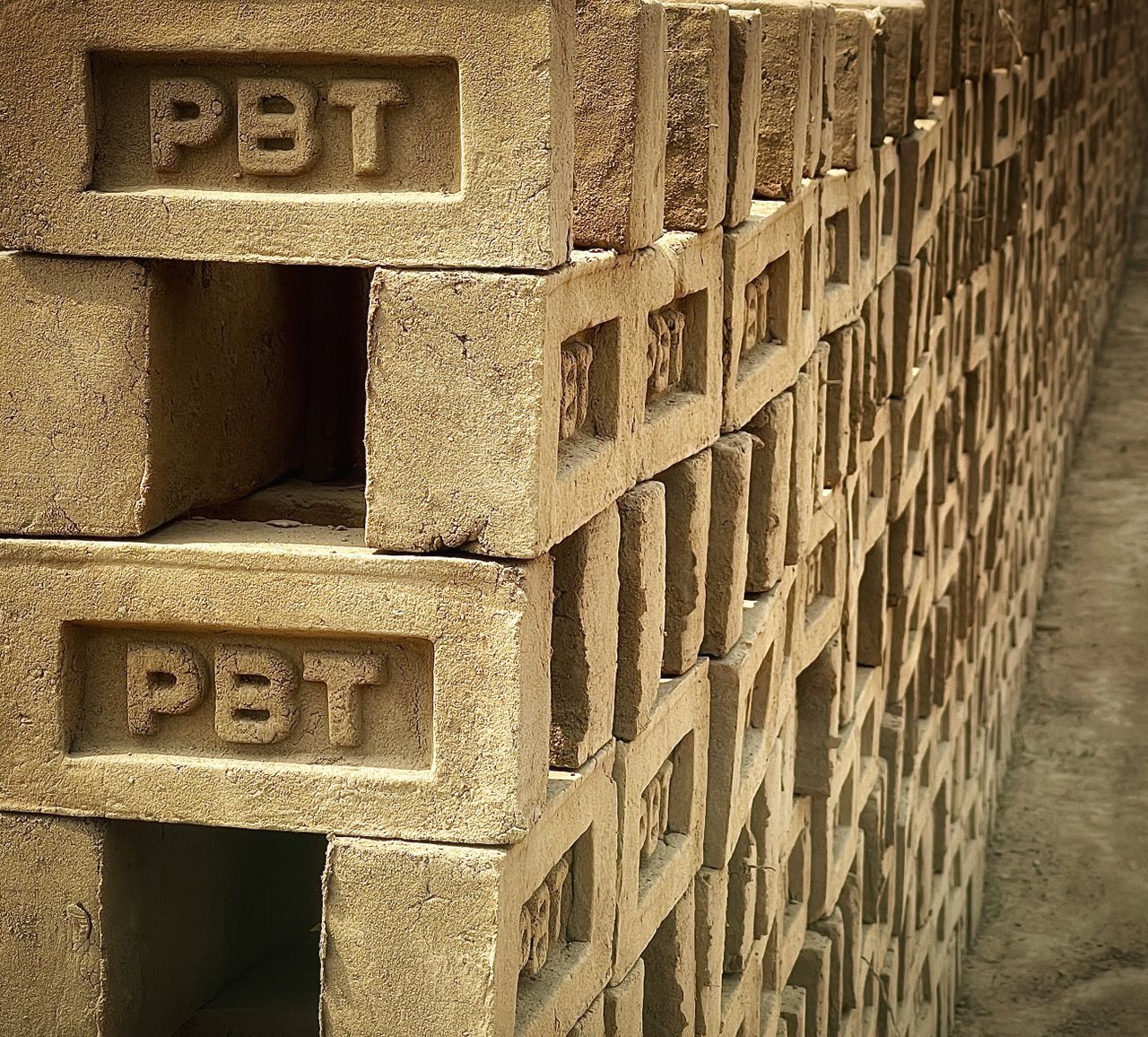 Close-up of stacked concrete bricks inscribed with PBT, showcasing industrial material.
